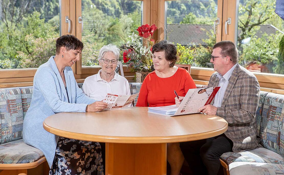 4 Personen besprechen sich an runden Tisch